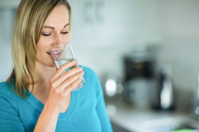 jeune femme boit une eau riche en calcium et magnésium